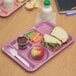 A Carlisle rose granite 6 compartment tray with a sandwich, apple, carrot, and other food on a table in a school cafeteria.
