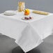 A white Hoffmaster Cellutex tablecloth on a table with plates and food on it.