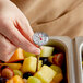 A person using a Taylor pocket probe thermometer to measure the temperature of a fruit salad.