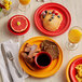 A table with Acopa Capri passion fruit red stoneware monkey dishes filled with breakfast food and drinks.