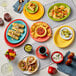 An oval yellow Acopa stoneware platter on a table with colorful plates of food.