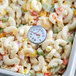 A Taylor pocket probe thermometer in a bowl of pasta salad.