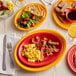 A table set with Acopa Passion Fruit Red oval platters of food and drinks.