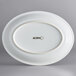 An Acopa coconut white stoneware oval platter with a white rim.