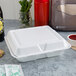 A white Dart foam container with 3 compartments holding food, a drink, and a bottle of sauce.