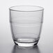 A clear Duralex glass tumbler with a curved rim on a white surface.