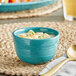 An Acopa Capri Caribbean turquoise stoneware bouillon bowl filled with soup and a spoon.