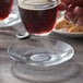 A hand pouring coffee into a Duralex glass saucer.