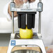 A person using a Vollrath Redco InstaCut 3.5 machine with a Vollrath 8-section wedge blade to cut a lemon.