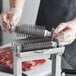 A person using a Backyard Pro Butcher Series tenderizer blade to cut meat.
