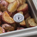 A Comark pocket probe thermometer in a tray of potatoes.