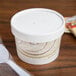 A Solo Symphony paper soup container with a lid and a spoon inside.