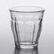 A Duralex Picardie clear glass stackable tumbler with a curved rim on a table.