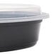 A black Pactiv Newspring oval plastic container with a clear lid.