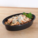 A Pactiv Newspring black oval microwavable container of pasta with cheese and parsley.