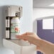 A hand using a white Rubbermaid Microburst air freshener refill to put into a white dispenser.