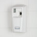 A white Rubbermaid Microburst 3000 air freshener dispenser on a tile wall.