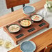 A Valor cast iron casserole dish display with bowls of food on a table.
