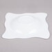 A white square shaped bowl with a small wavy design on the rim.