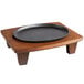A black oval cast iron plate on a wooden stand.