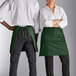 A man and woman wearing Choice hunter green half bistro aprons with pockets.