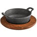A Valor black cast iron round serving bowl on a rustic wooden underliner.