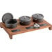 A Valor wooden tray with three cast iron pots and a chalkboard on a rustic display stand.