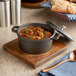 A Valor pre-seasoned cast iron pot of stew on a wood board with bread and a spoon.