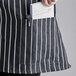 A person wearing a Choice black and white chalk striped half bistro apron with pockets.