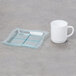 A Fineline green plastic tray with a white mug on a grey surface.