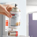 A person holding a Rubbermaid Microburst 9000 Ocean Breeze metered aerosol air freshener refill can.
