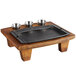 A rectangular black cast iron pan on a wood table with three bowls on it.