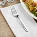 An Acopa stainless steel salad fork on a plate of salad.