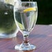A close-up of a Libbey Banquet Goblet filled with water and a lemon slice on a table.