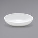 A Front of the House white oval ramekin on a gray surface.
