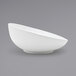 A close-up of a white Front of the House Ellipse porcelain bowl with a curved edge.