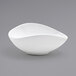 A white oval porcelain ramekin with a curved edge.