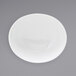 A white oval porcelain bowl with a white rim on a white surface.