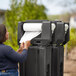 A woman using a Cambro black portable handwash station to dispense paper towels.