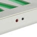 A close up of a white and green Lavex Slim LED Exit Sign with a red button.