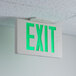 A white Lavex green LED exit sign with green lit up text on a ceiling.