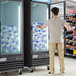 An Avantco ice merchandiser with a glass door in a grocery store aisle.