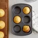 A Wilton jumbo muffin pan with six yellow muffins in it.