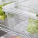 Two Cambro clear plastic food storage containers with vegetables in them.