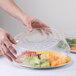 A person holding a Durable Packaging clear plastic lid with fruit on a plastic container.