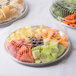 A Durable Packaging clear plastic high dome lid on a group of plastic containers filled with assorted fruit and vegetables.