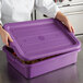 A woman closing a Vollrath Traex purple food storage box lid.