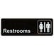 A black and white rectangular sign that says "Restrooms" with images of a man and woman.