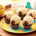 A plate of cupcakes with brown frosting in the shape of hedgehogs.