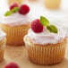 A Wilton Recipe Right cupcake with raspberries and a mint leaf.